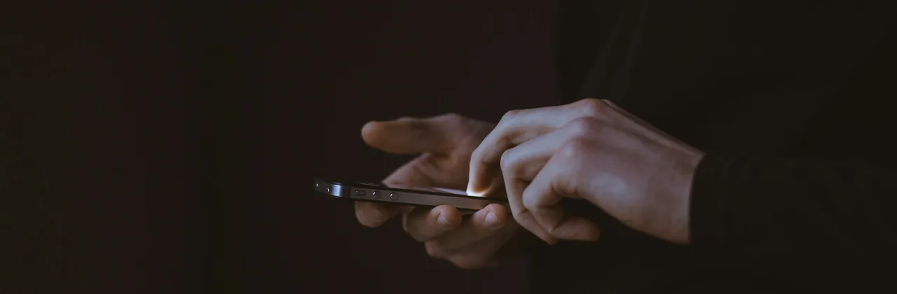 Hands using a phone in near-darkness
