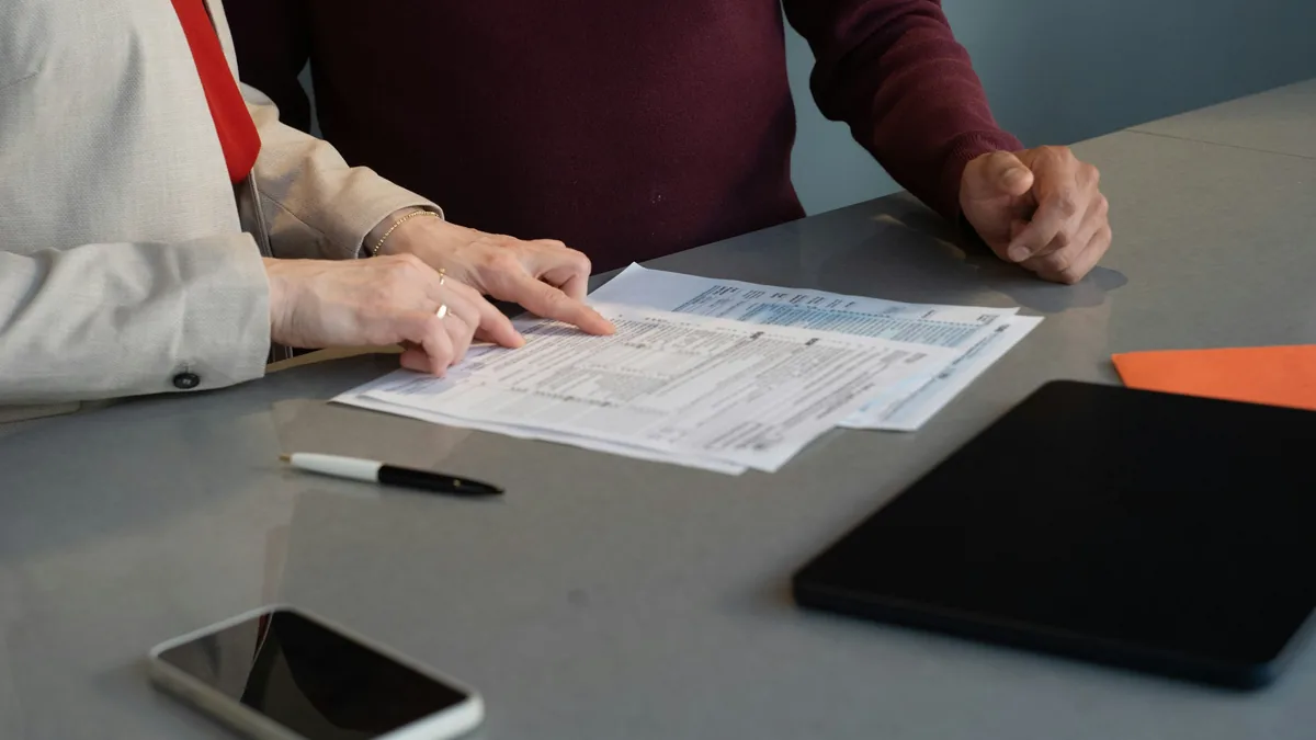 Two people going through a paper form at a table