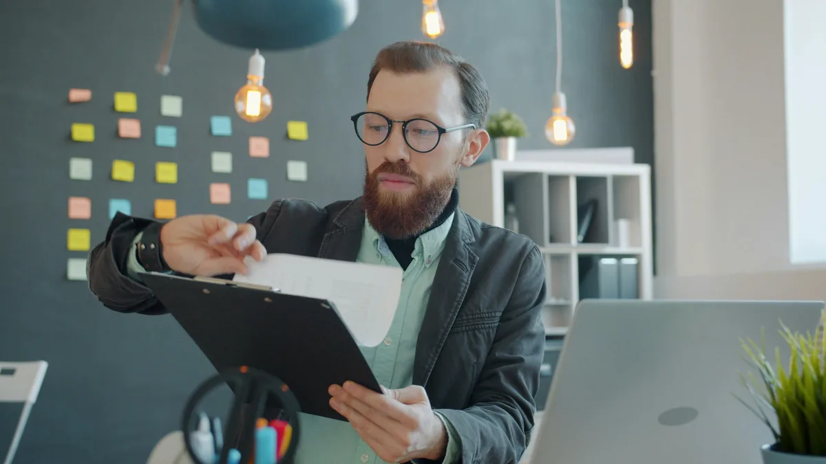A person in glasses reading a document at a desk