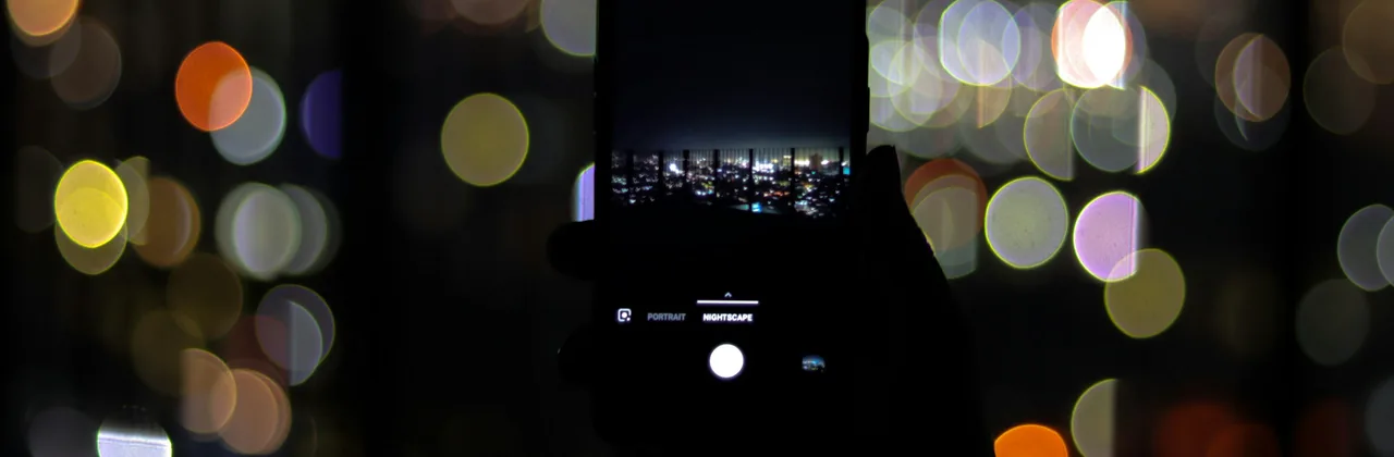 A phone held up at night against coloured bokeh