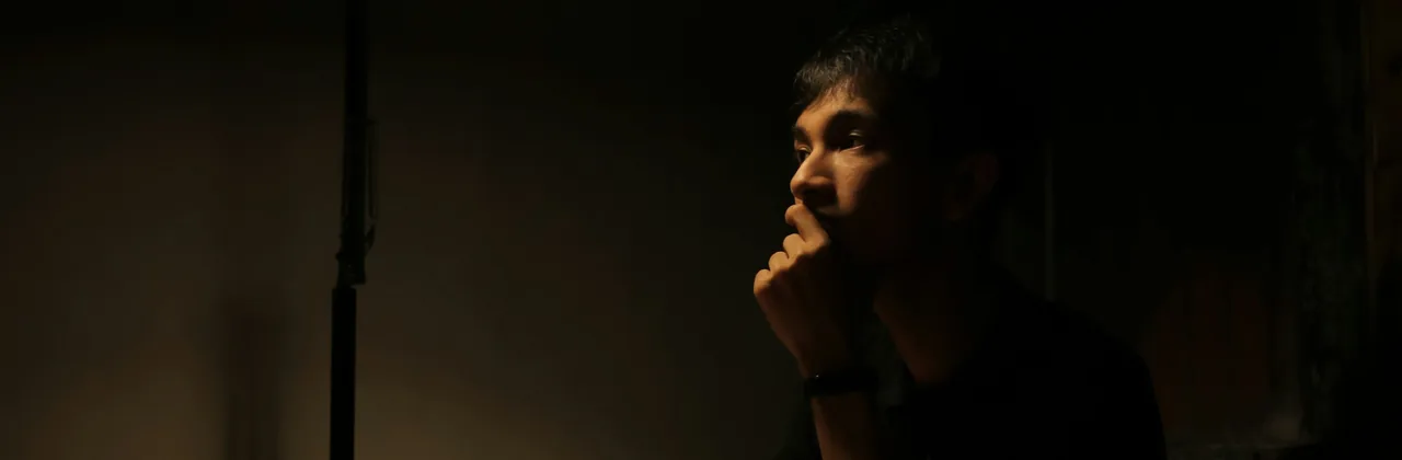 A person sitting alone at a table in a dim room